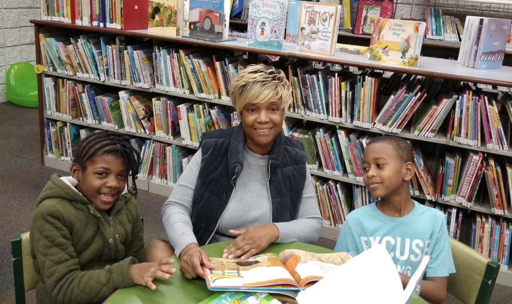 Trudy Jackson posing with kids as she helps them with homework.