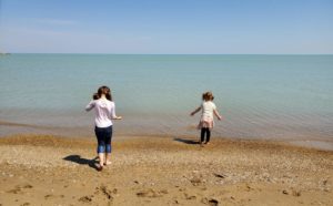 two young girls explore the shoreline of a beach