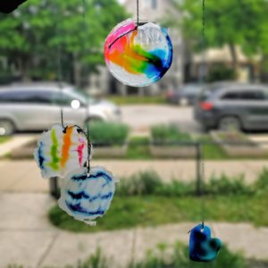 Colorful glue suncatchers hang in a window.