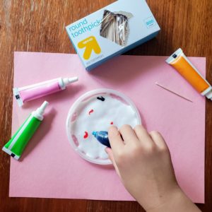 A child drops food coloring on glue.